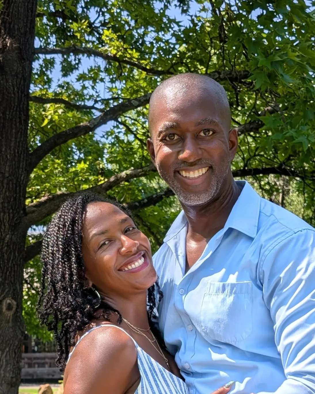 Damian and Merkieann, the founders of Graitness, smiling together beneath green trees.